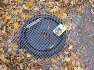 Photo of the lid lying on the ground along with all the
materials and most of the tools I used for the job. Tools shown are
needle-nosed pliers and tin snips.